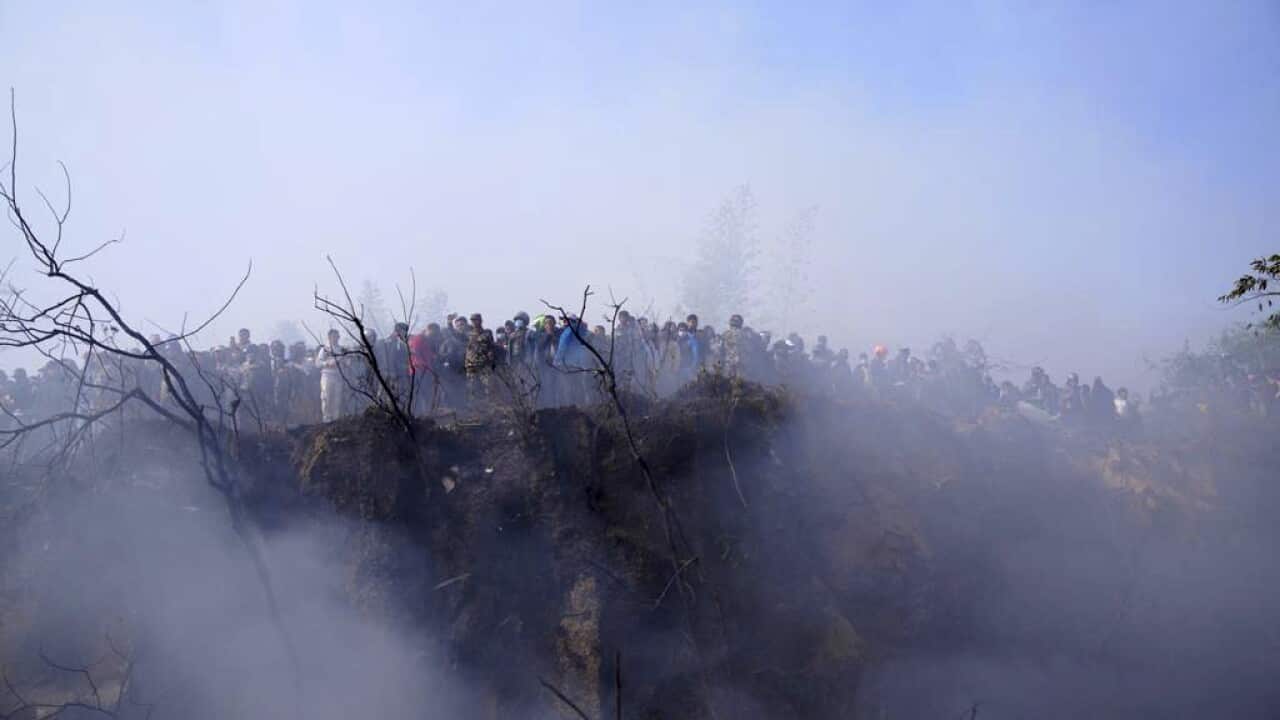 Locals watch the wreckage of a passenger plane in Pokhara, Nepal.