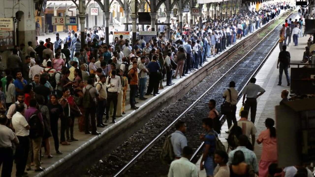 Commuters wait to board a train at the Fort railway station in Colombo, Sri Lanka,