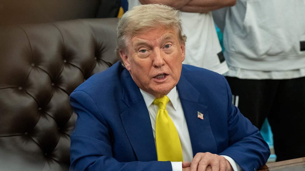 US President Donald Trump sits at the wooden desk in the Oval Office of the White House.