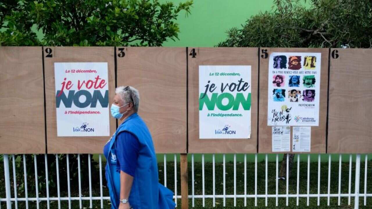 A woman walks past electoral boards near a polling station in Noumea ahead of the third referendum on independence