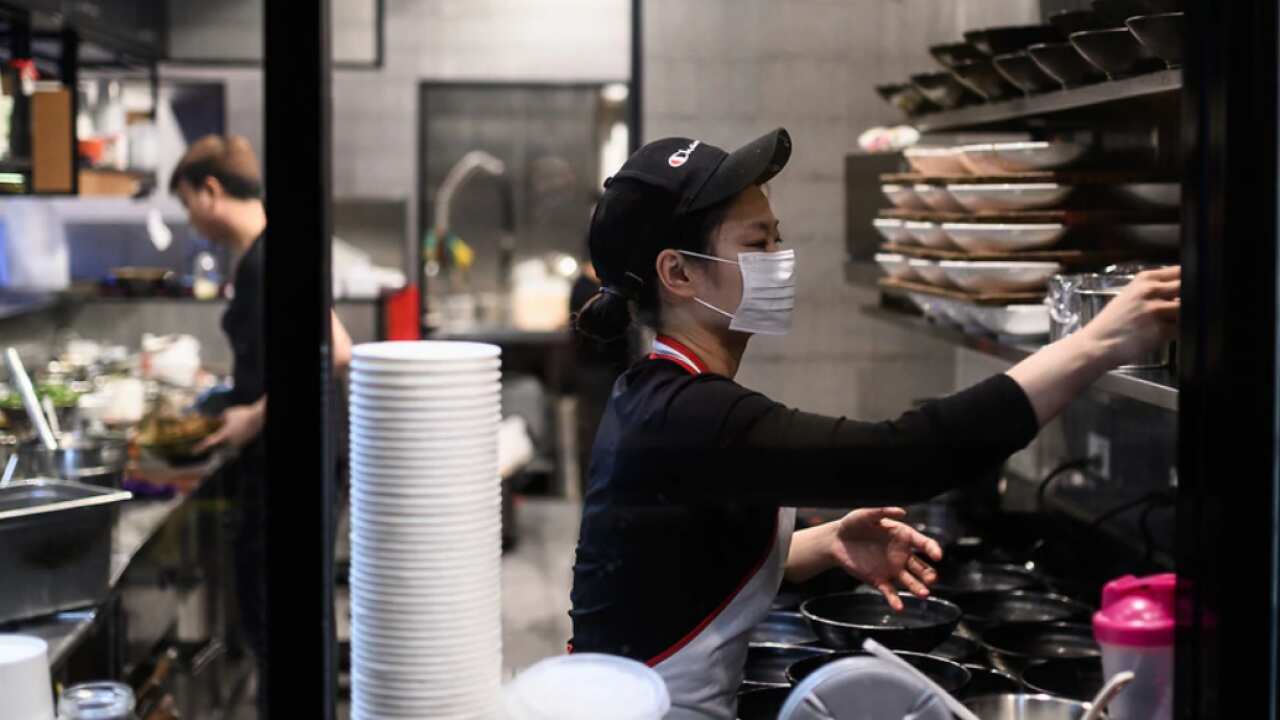 A woman seen wearing a protective face mask in a restaurant kitchen in Sydney.