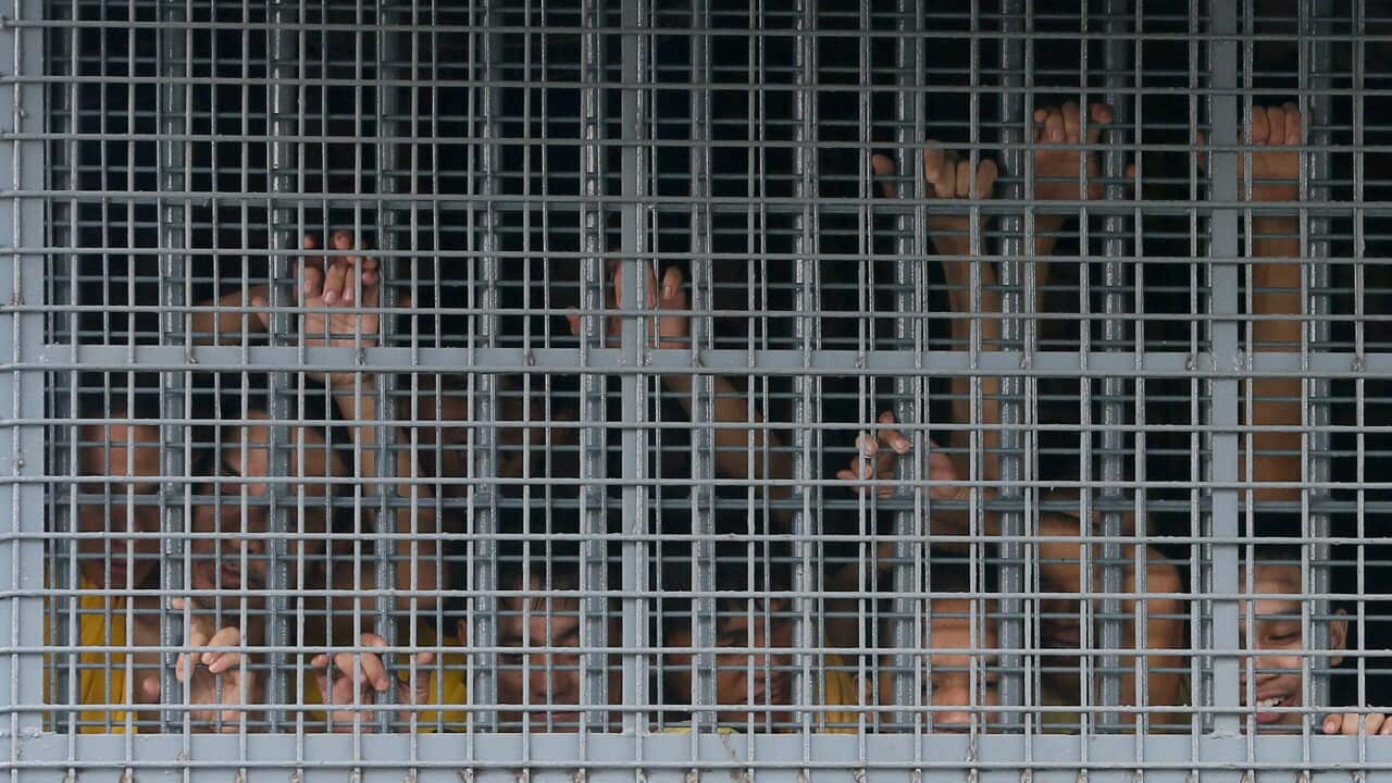 Prisoners hold on to the prison window grill in the Philippines.