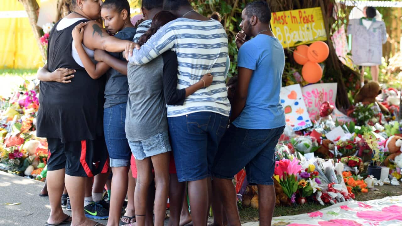 Mourners comfort each other while attending a floral tribute in Cains