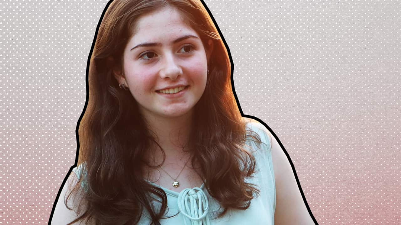 A young woman smiles and looks off-camera