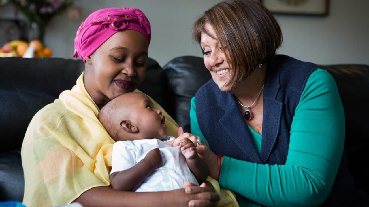 Volunteer doula Elizabeth Mazeyko (right) visits a mother and her new baby.