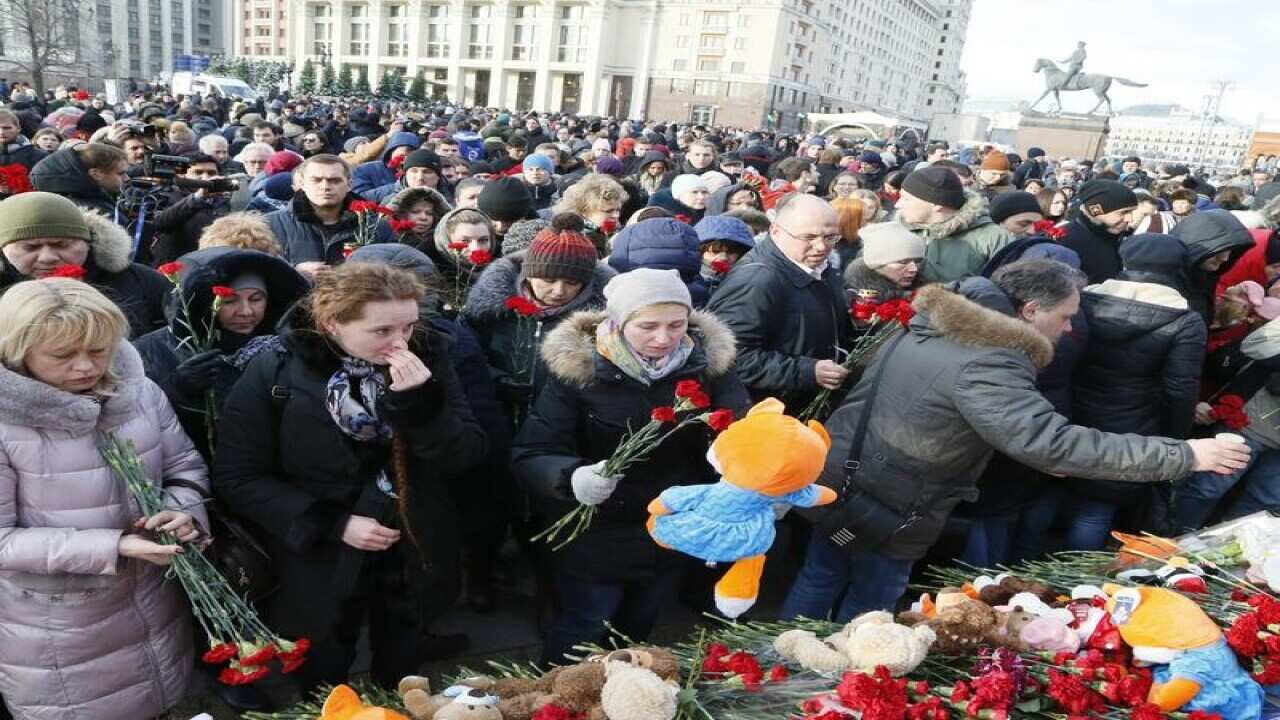 People lay gifts at a memorial for victims of a fire in Russia.