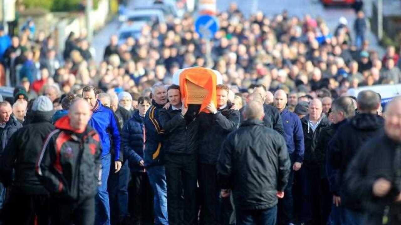 Fiachra McGuinness (C-L) and Emmet McGuinness (C-R) carry the coffin of their father Martin McGuinness through the streets the Bogside area of Derry