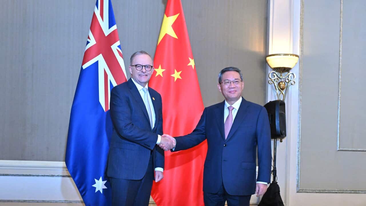 Australian Prime Minister Anthony Albanese shakes hands with Chinese Premier Li Qiang in front of flags of both countries. Both are wearing suits