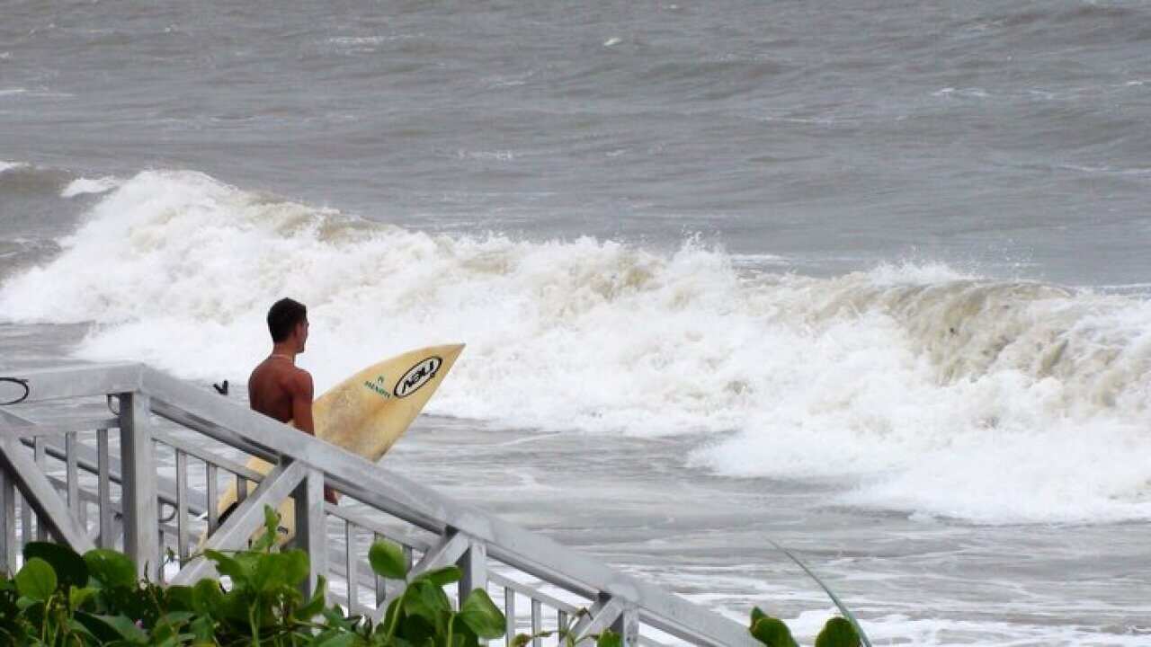 A surfer makes his way into the swell on Yeppoon's main beach