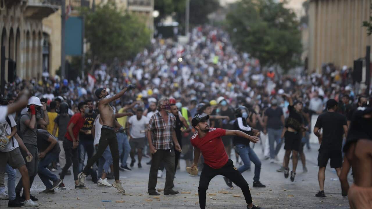 People throw stones during anti-government protest following Tuesday's massive explosion which devastated Beirut, Lebanon, Sunday, Aug. 9. 2020. (AP Photo/Hassan Ammar)
