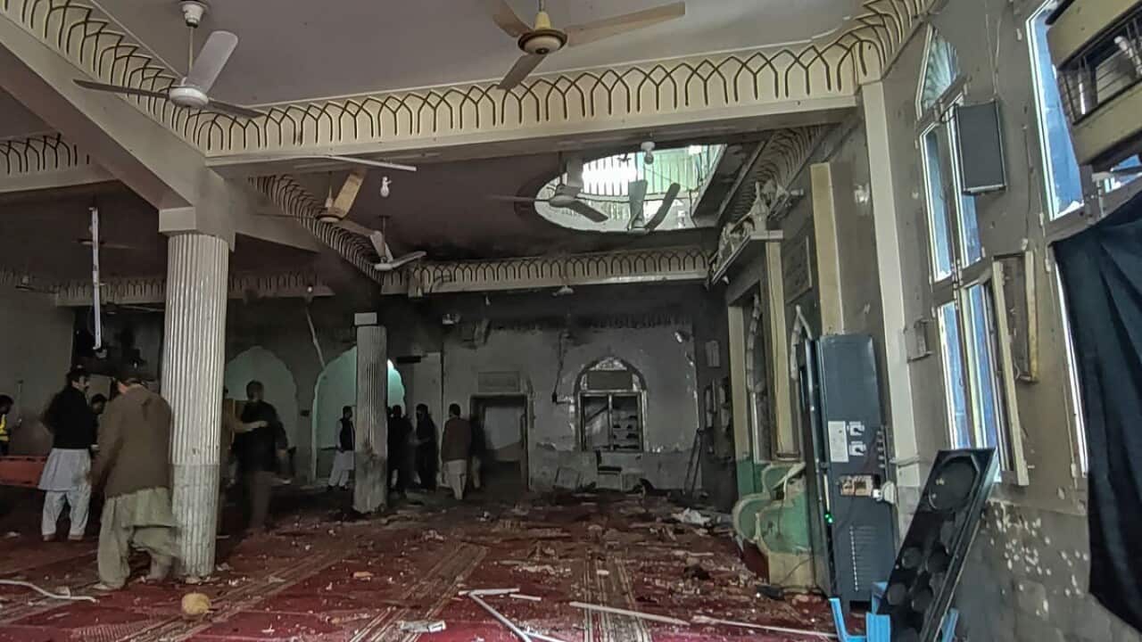 Volunteers examine the site of an explosion inside a mosque in Peshawar