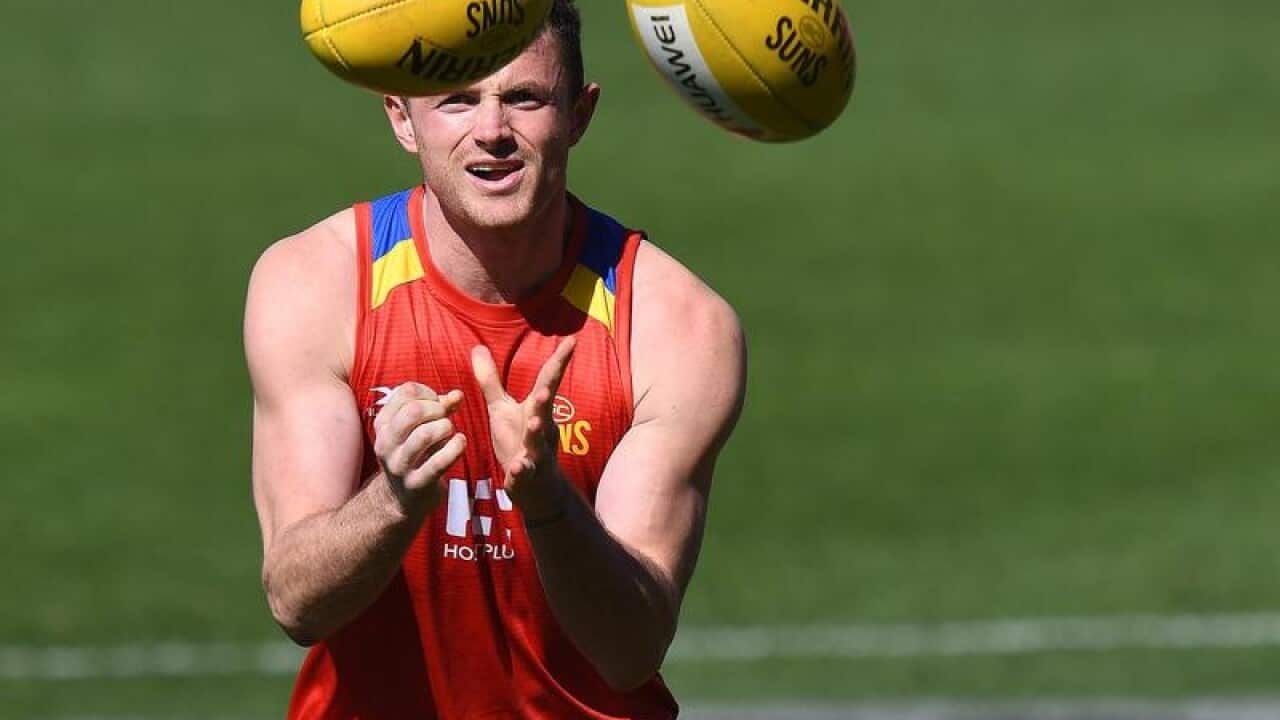 Pearce Hanley handballs during Gold Coast Suns training