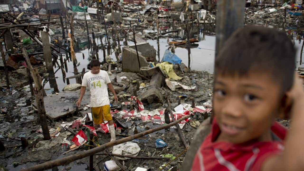 A boy helps his father slavage belongings from their destroyed house