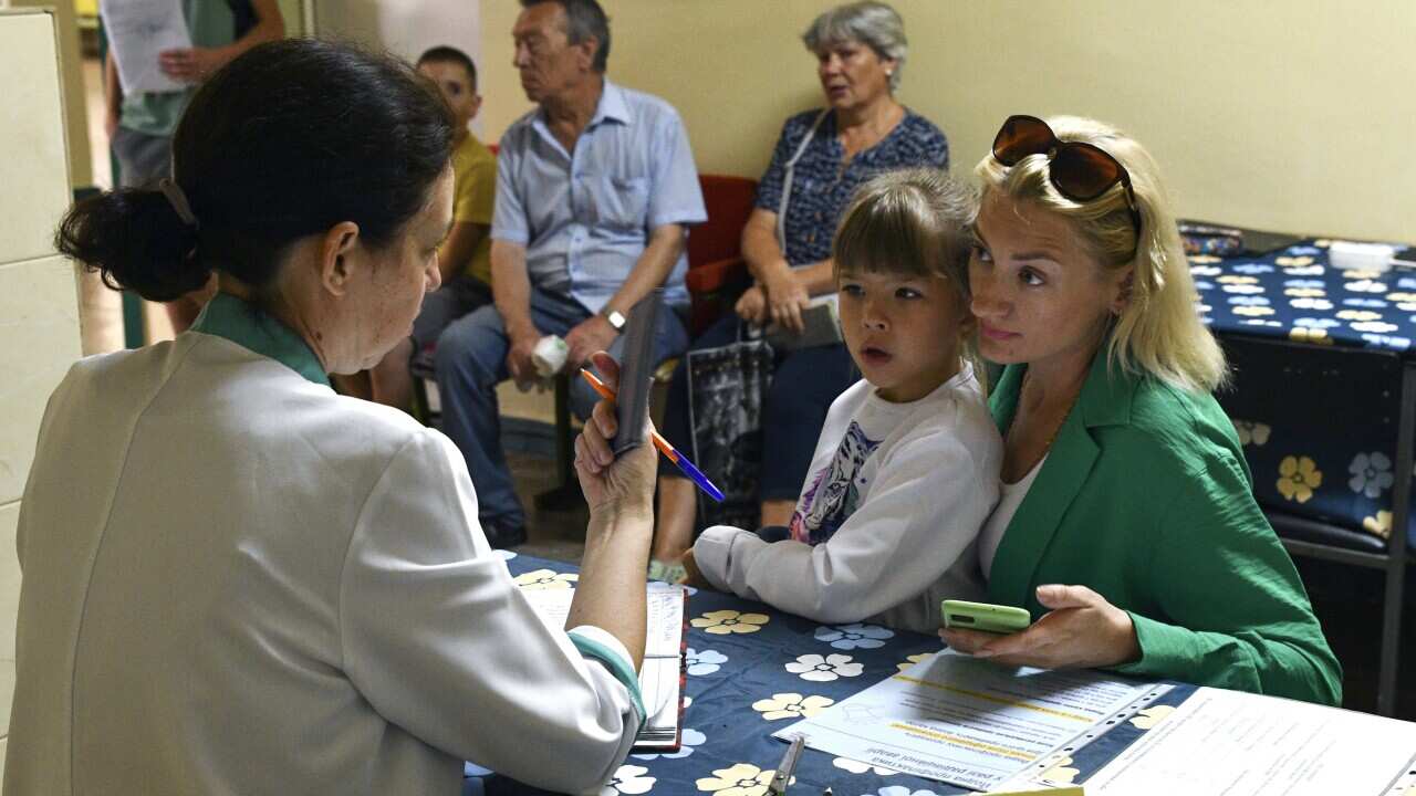 A woman and a child receive iodine-containing tablets at a distribution point in Zaporizhzhia, Ukraine.