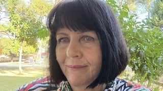 a middle aged woman with a black bob haircut takes a selfie in a front yard