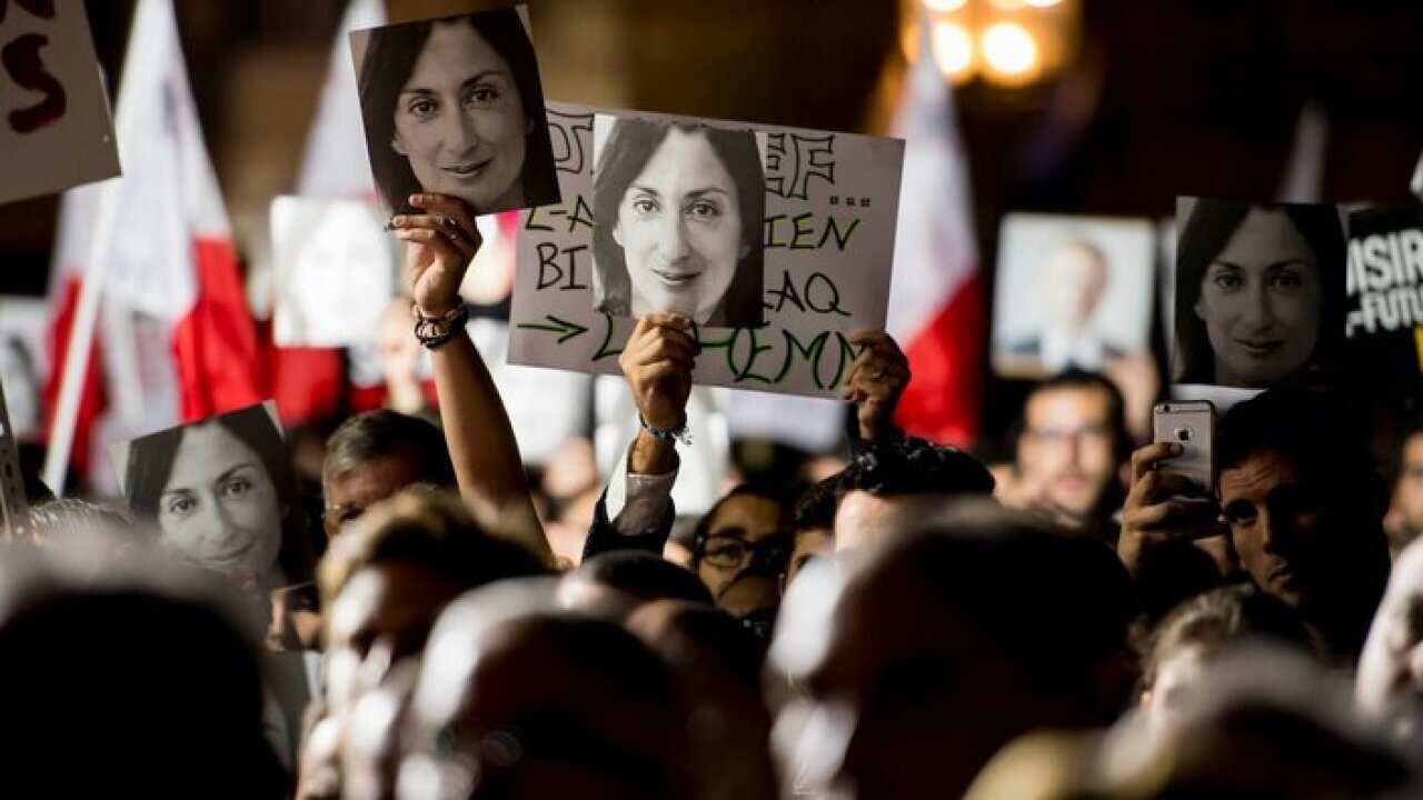 Protesters hold photos during a protest outside the office of the PM of Malta