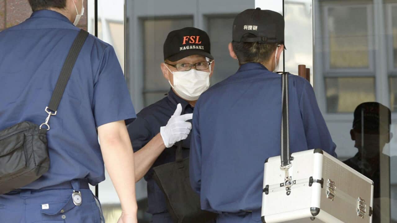 Japan - Police officers enter an apartment building in Sasebo