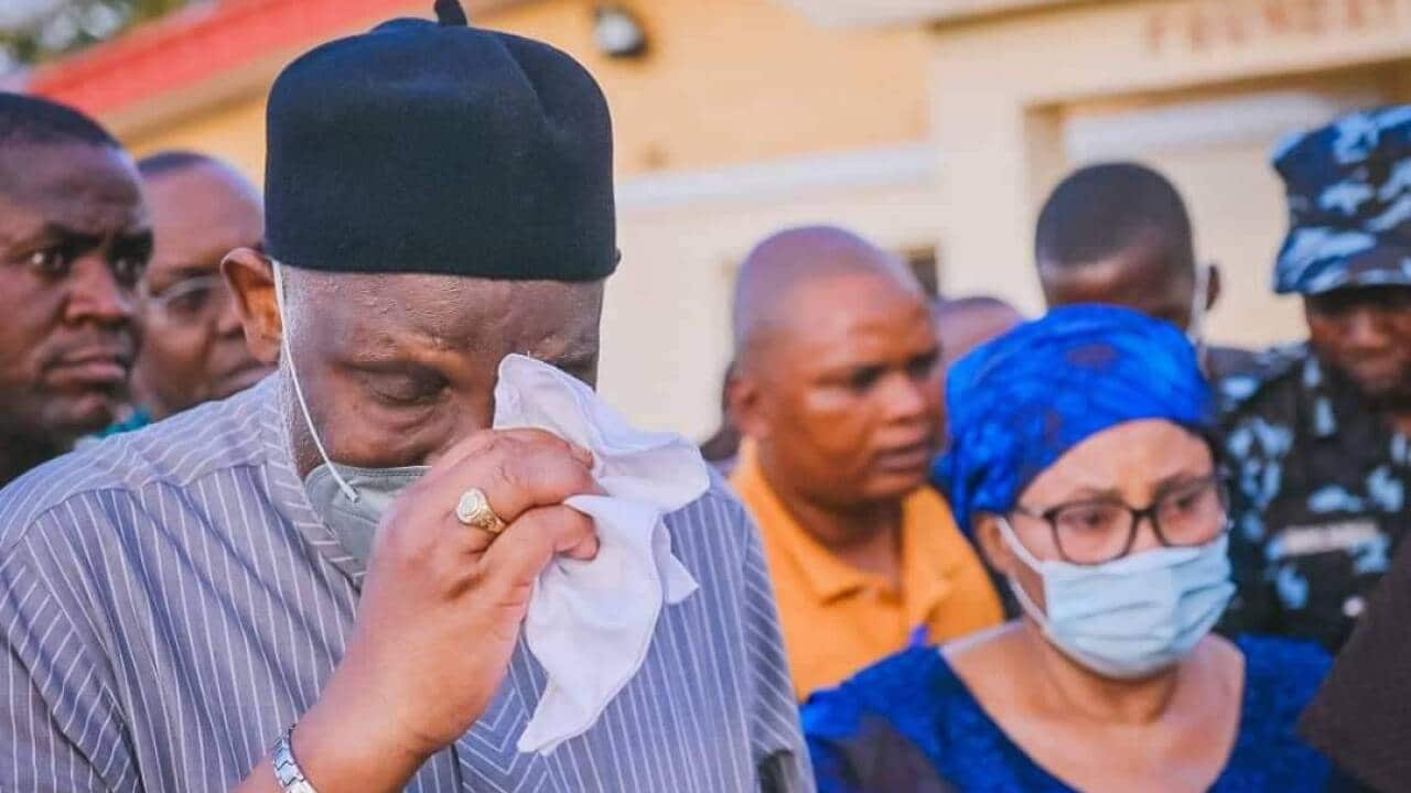 A man wearing a face mask wiping his eyes