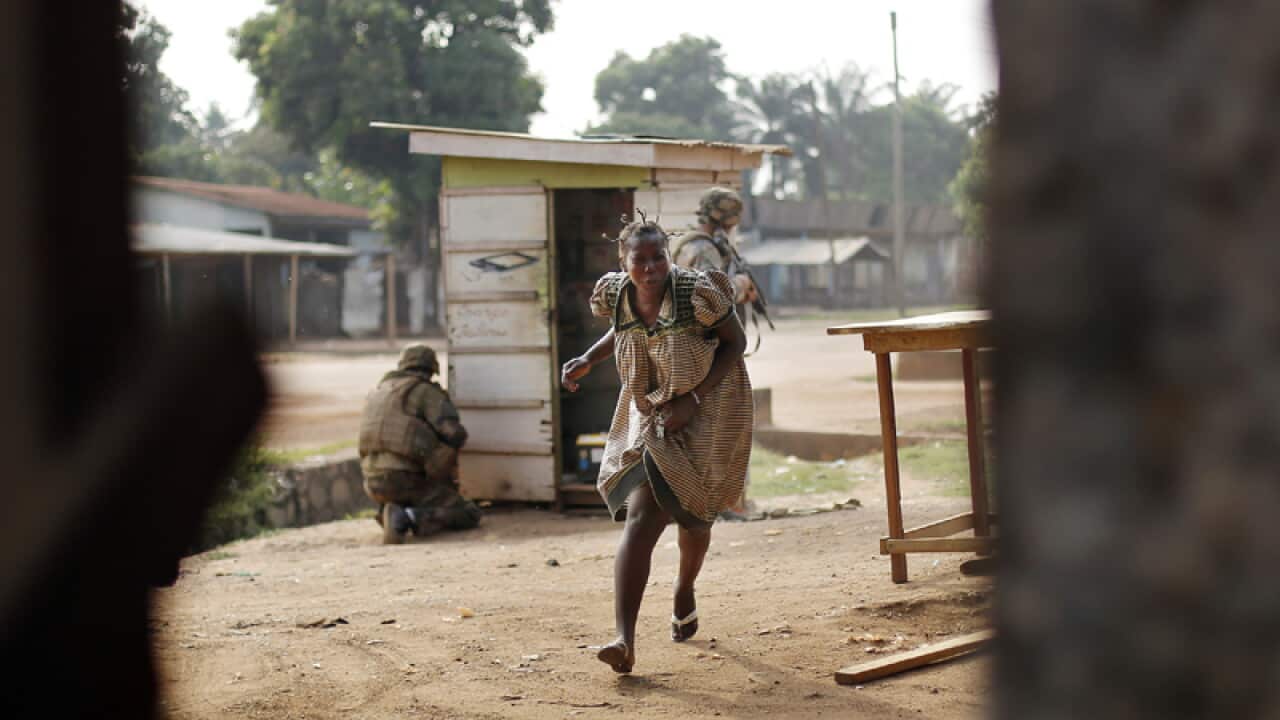 A woman runs for cover as heavy gunfire erupts in Bangui