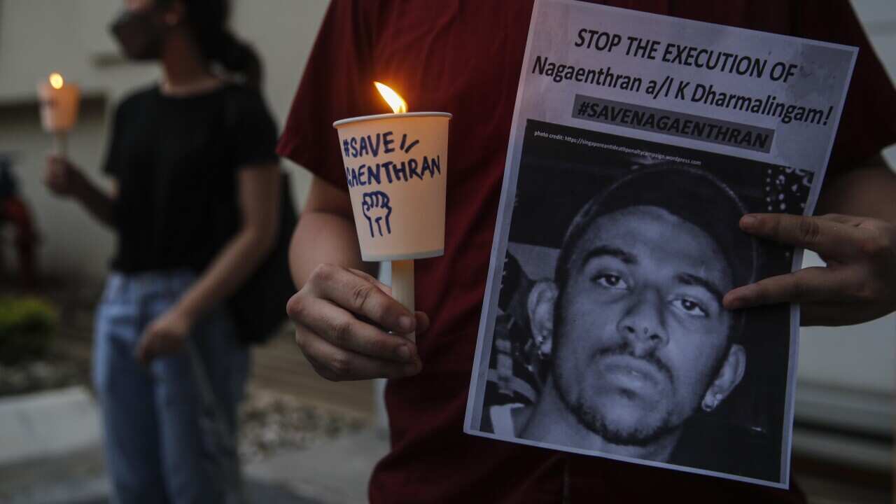 An activist holds a placard with candle during a vigil against the execution of Nagaenthran K Dharmalingam