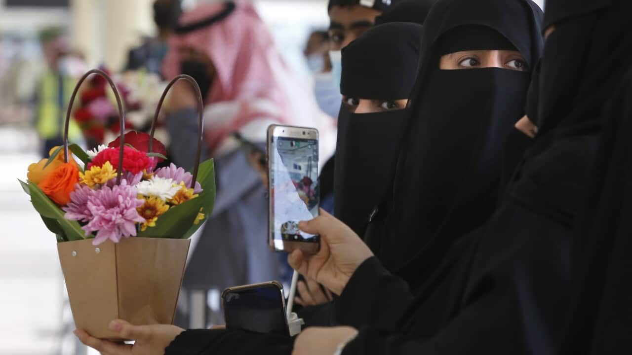 Saudi women hold flowers as they wait for the arrival of their Qatari relatives on the first Qatar Airways plane in three years to land at King Khalid Airport.