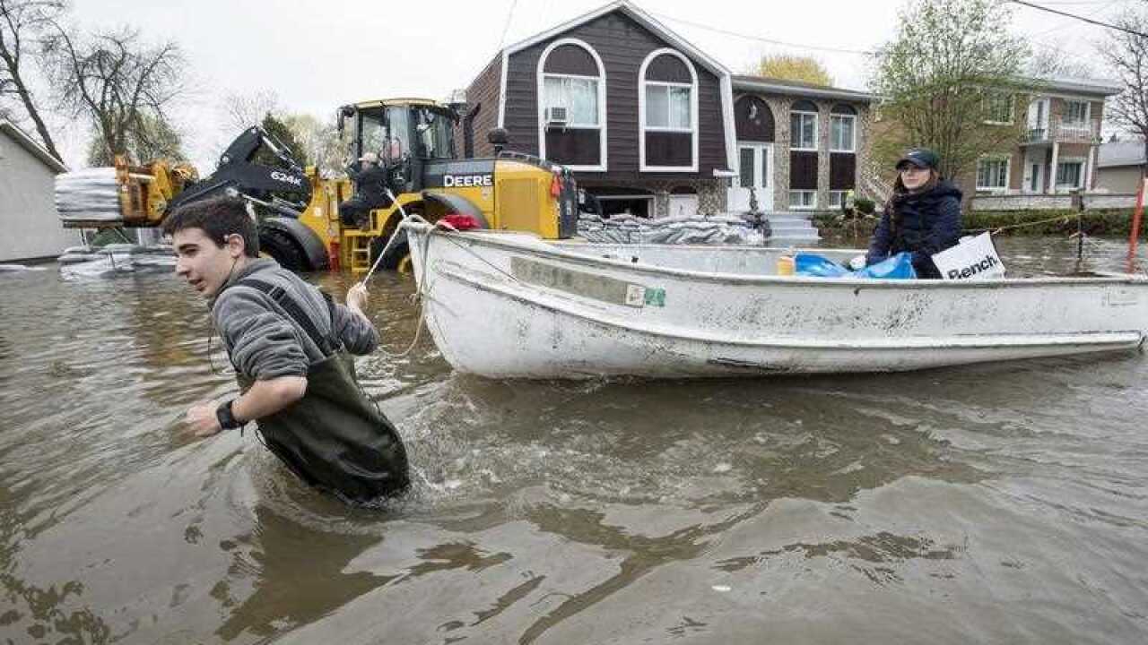 A man pulls a boat down a flooded street on Ile Bizard, Quebec, near Montreal.