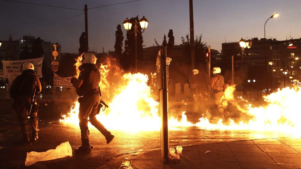Greek policemen try to avoid a petrol bomb