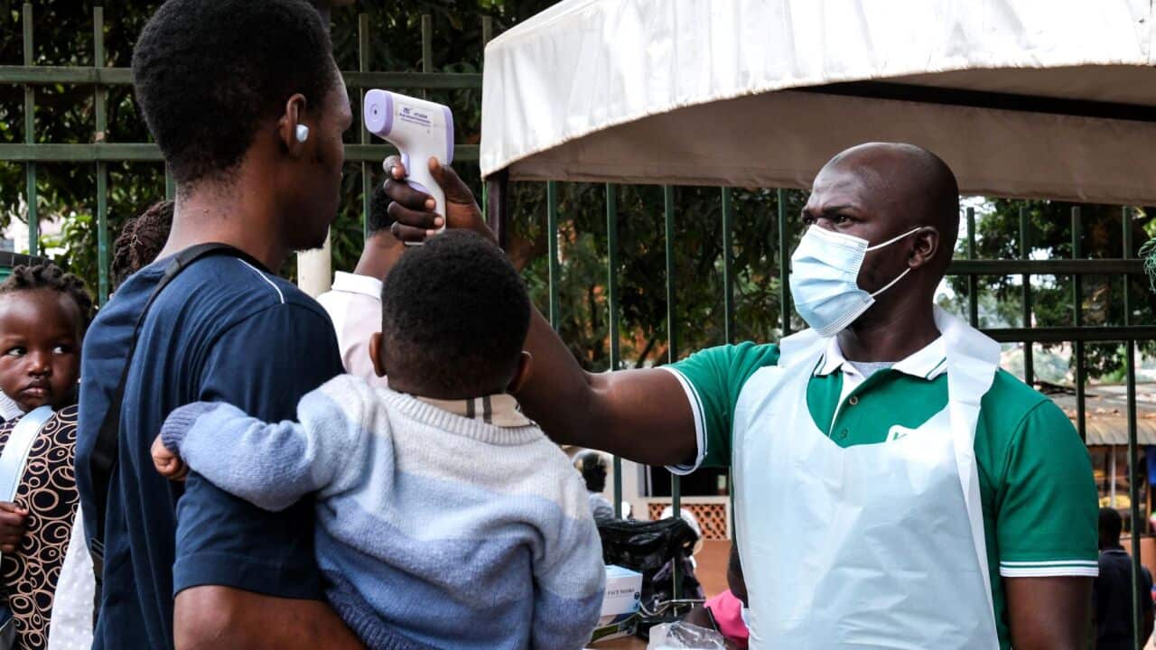 A health official uses a thermometer to screen people in front of Kibuli Muslim Hospital in Kampala, Uganda (AP Photo-Hajarah Nalwadda).jpg