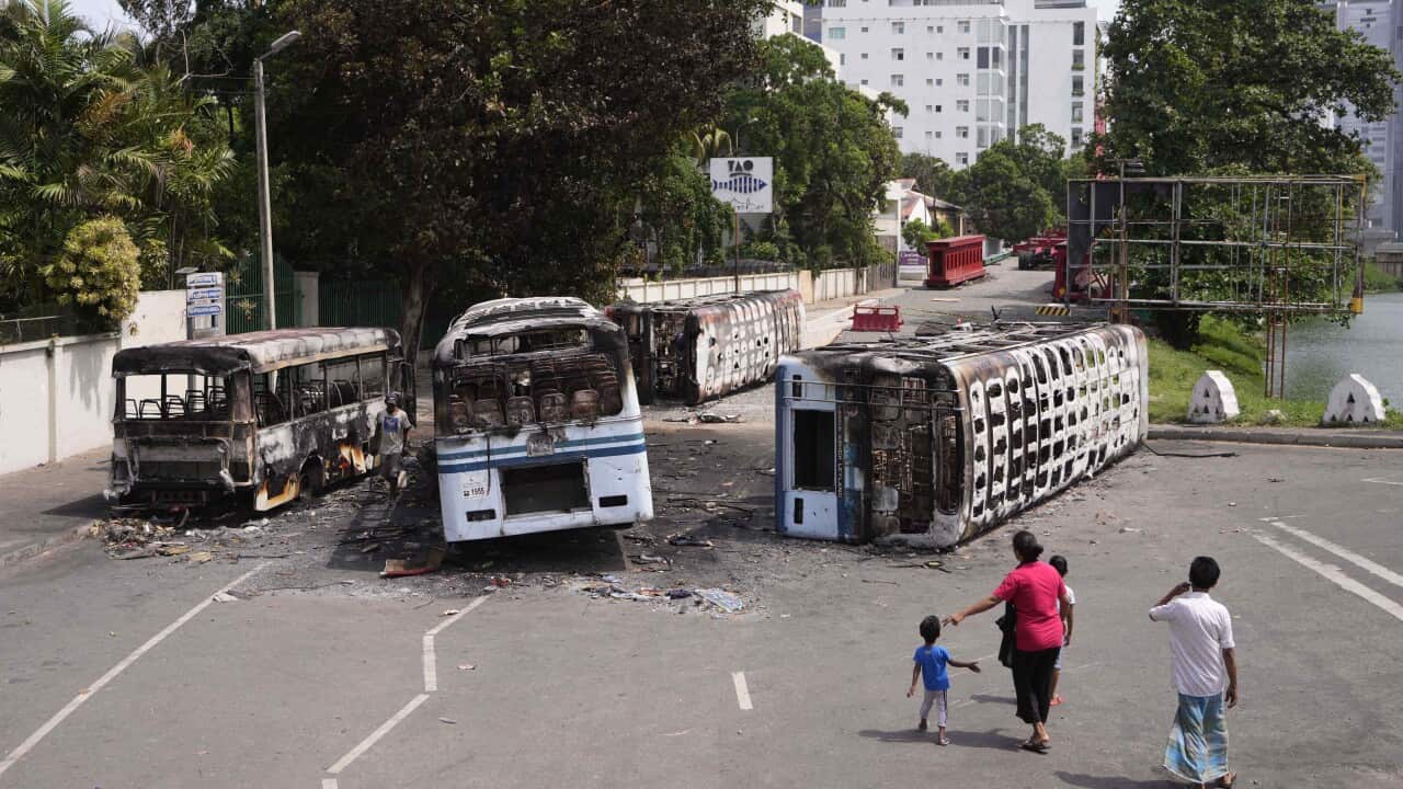 A child and his parents look at three burnt buses.