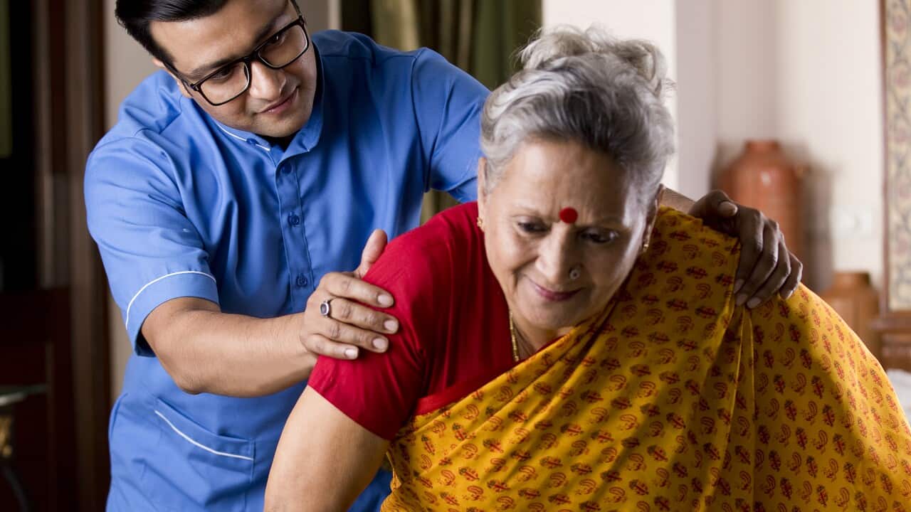 A male nurse assists a patient with knee pain.