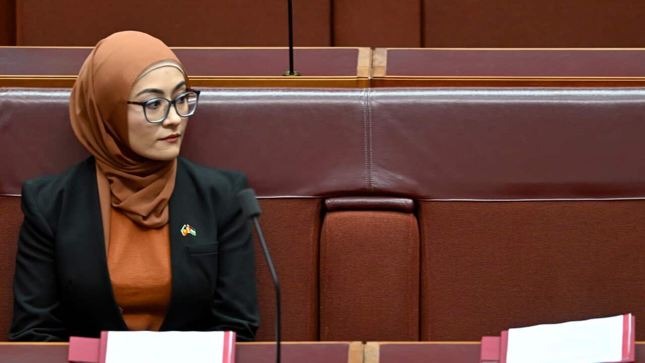 A woman with a headscarf sits on a couch