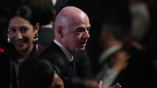 A bald man dressed in a dark suit in a crowd of people.