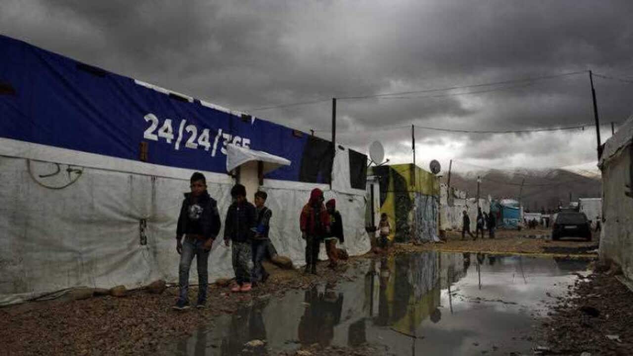 Syrian refugee children walk in mud after a heavy rain at a refugee camp in the town of Bar Elias, in Lebanon.