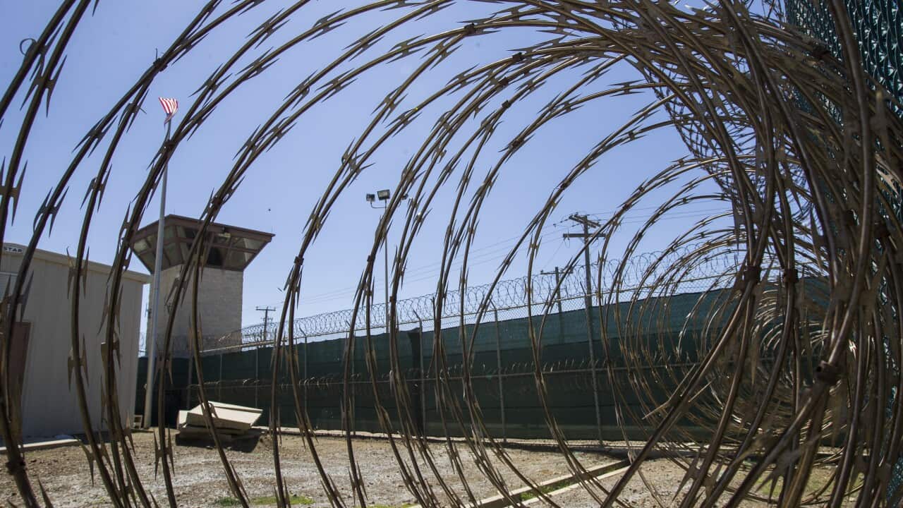 Barbed wire in front of a detention centre courtyard.