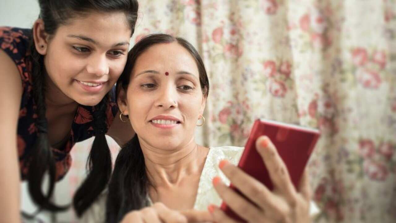 Mother and daughter using tablet together in domestic room.
