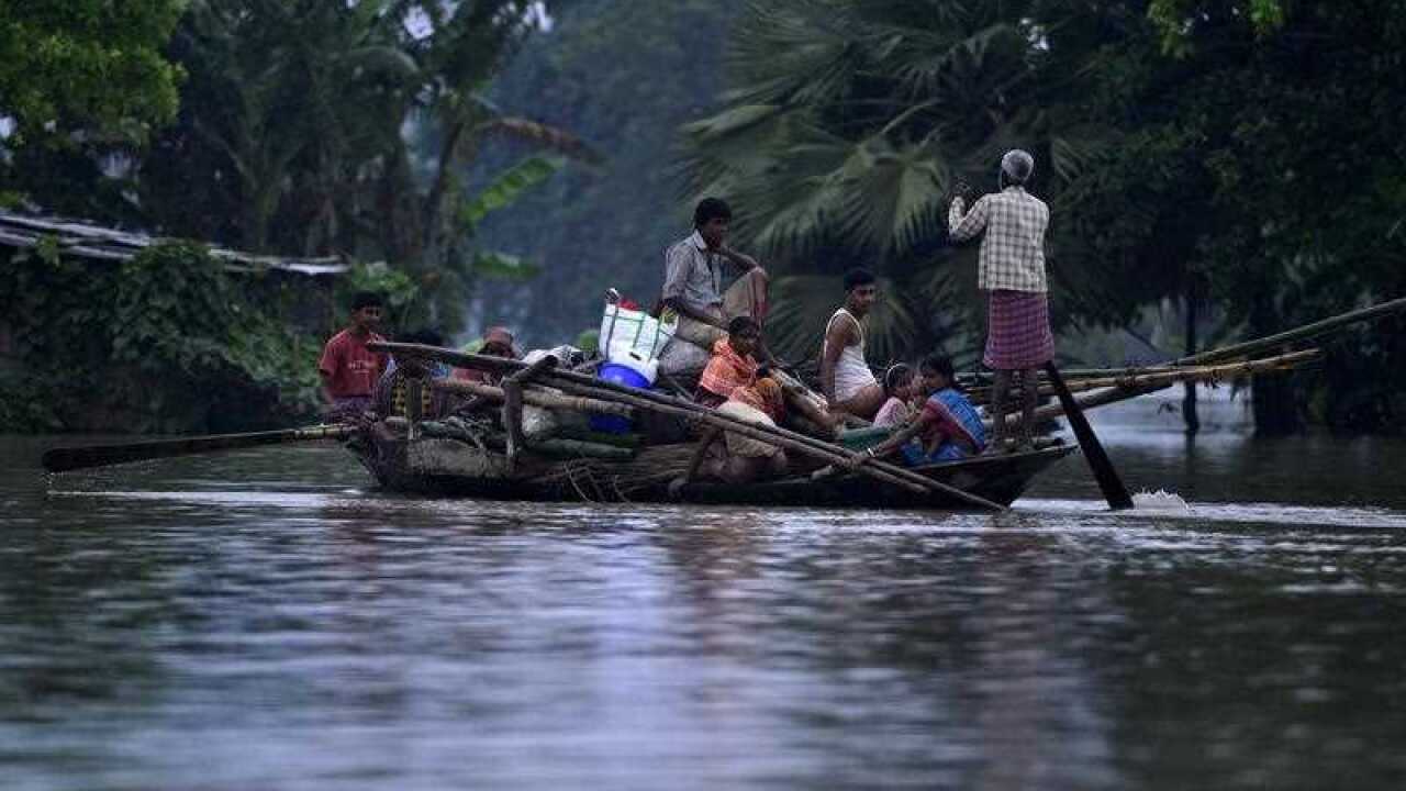 Indian villagers leave their flooded village to go to a relief camp.