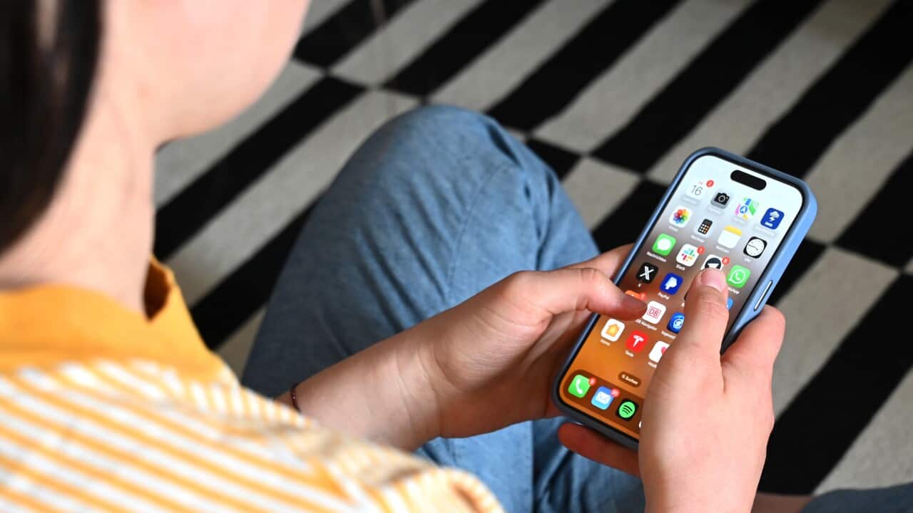 A person in a striped yellow shirt using an iPhone.