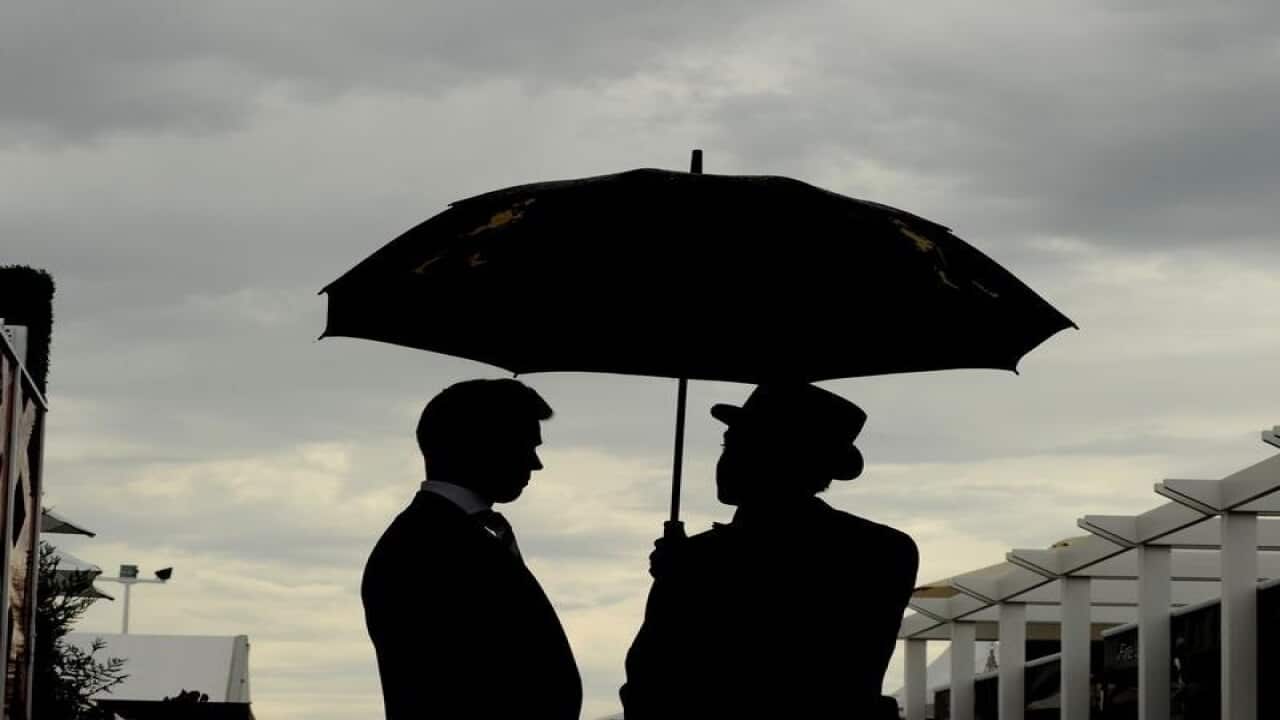 A file image of racegoers sheltering under an umbrella at Flemington