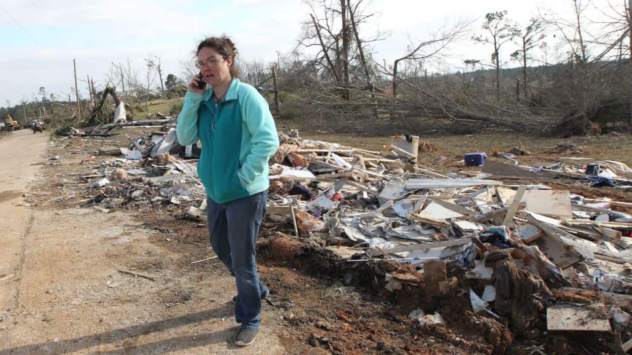 Shannon Kelley talks on the phone as she walks down her street after a tornado struck in Beauregard, Alabama.