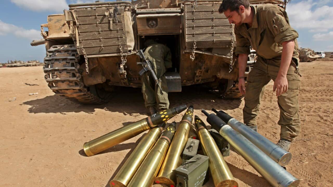 An Israeli soldier loads ammunition onto a tank