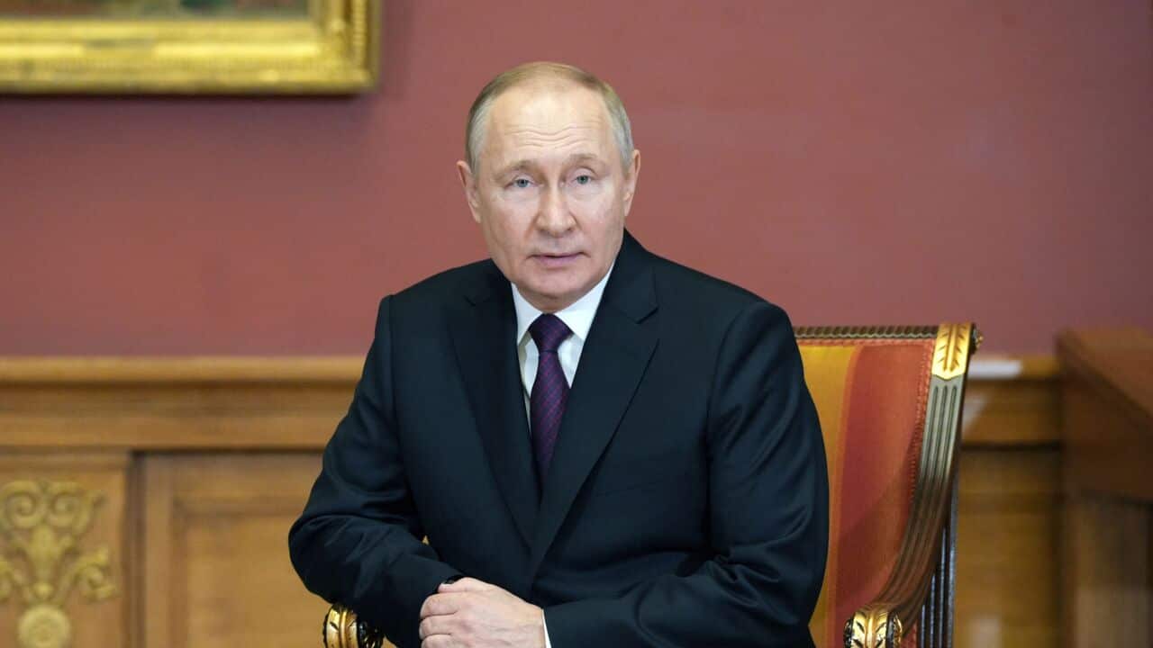 Vladimir Putin sitting in a chair posing for an official photo.