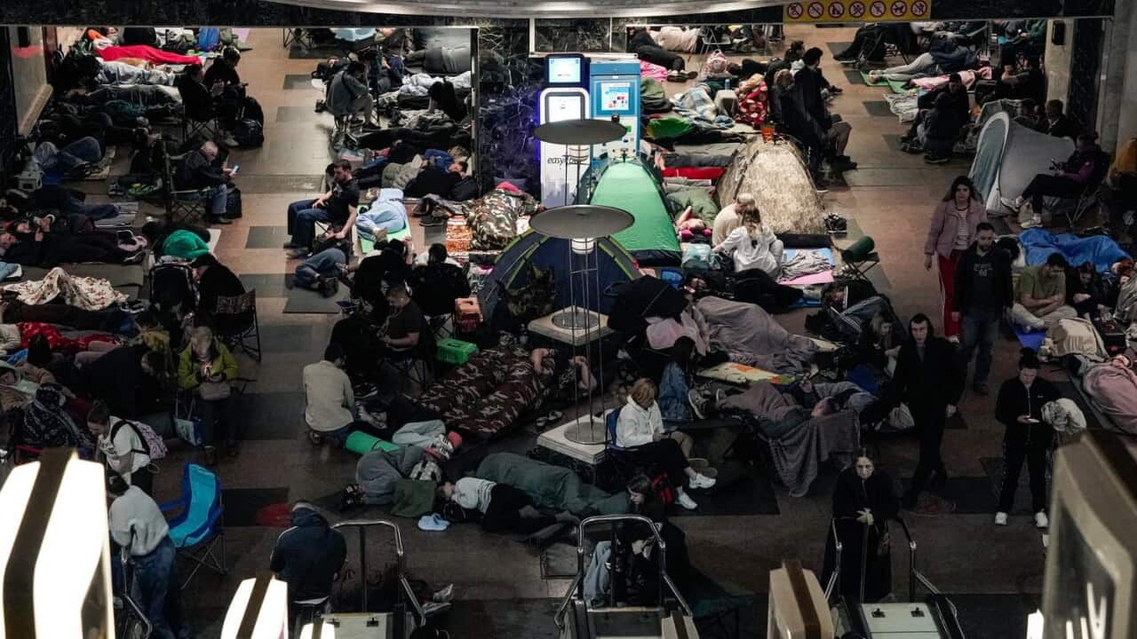 A group of people sheltering in an underground metro station.