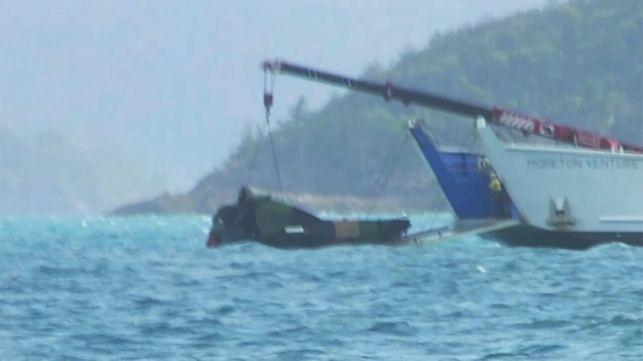 Grainy image of part of a helicopter being retrieved from the water.