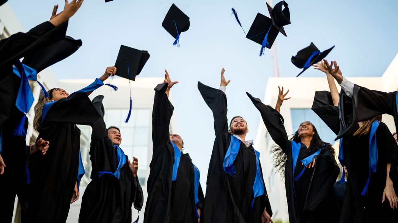 Young graduates throwing their mortarboard in the air while celebrating on graduation