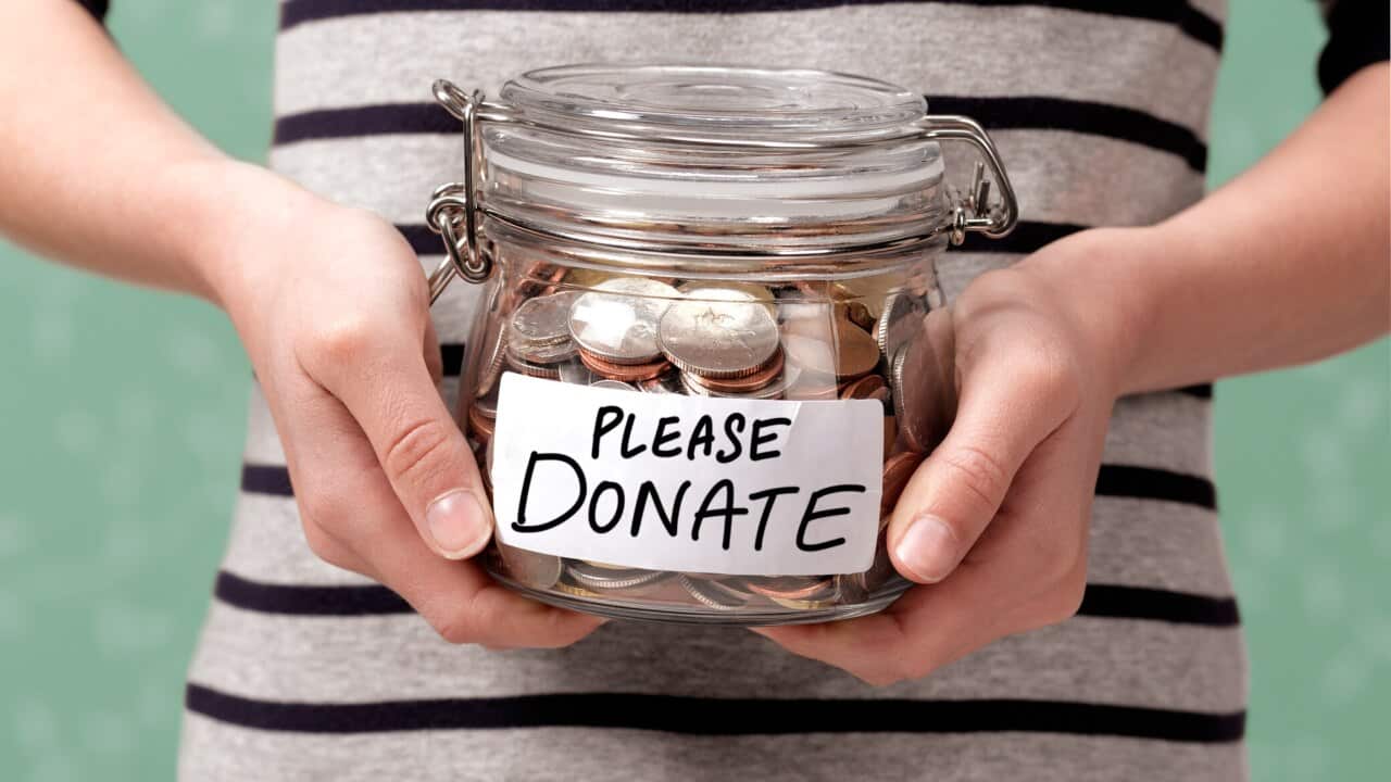 Close up of a girl holding a charity donation jar with coins in.