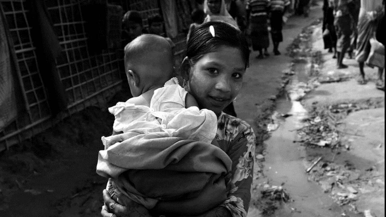 A Rohingya child carries another child