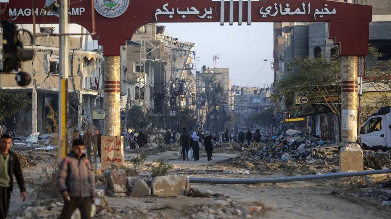 People walk through the rubble of destroyed houses and buildings.
