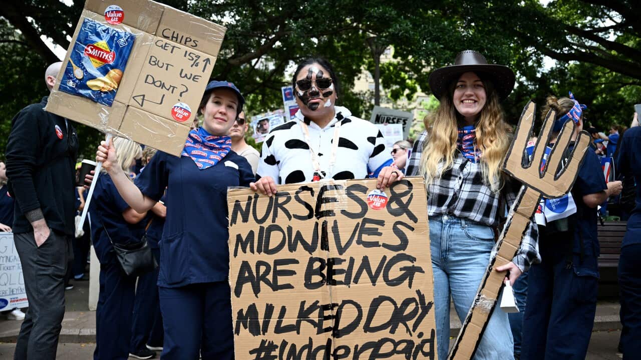 A large group of people standing at a basketball court that's serving as a voting centre.