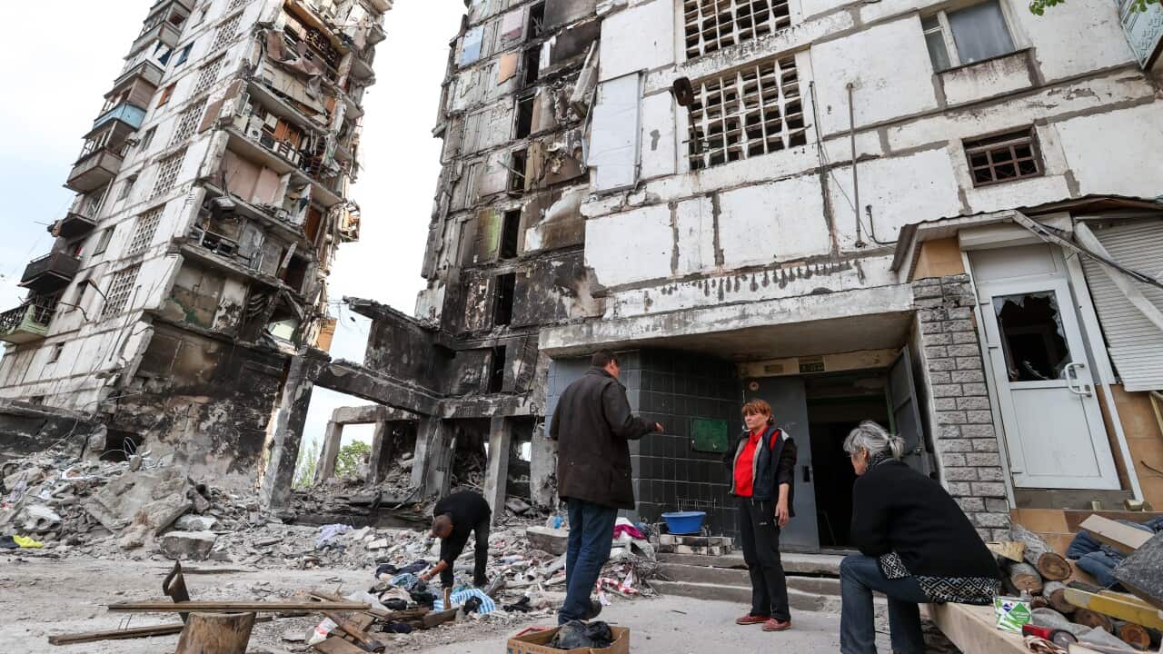 Local people are seen outside a badly damaged residential building in the city of Mariupol, Ukraine.