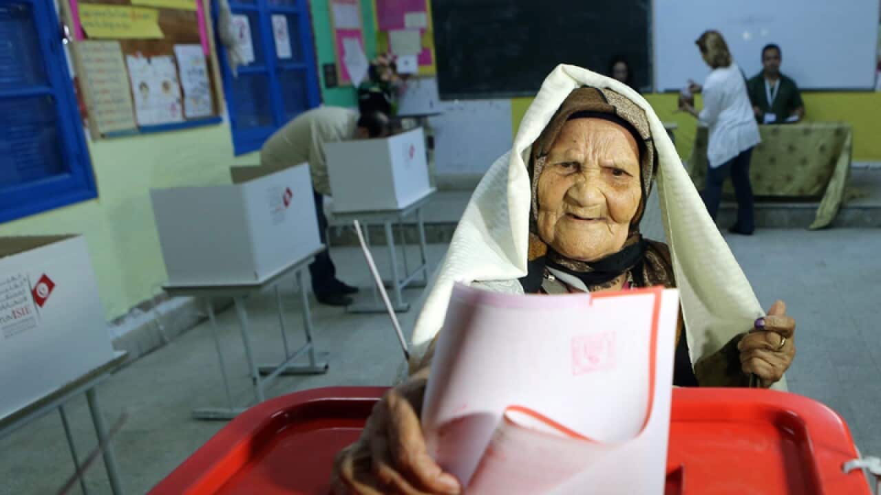 An elderly Tunisian woman casts her ballot